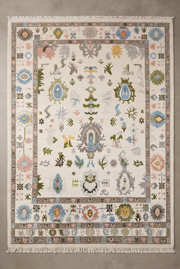 Ivory Caravan — hand-knotted rug with tribal motifs in sky blue, pink, olive and rust on ivory